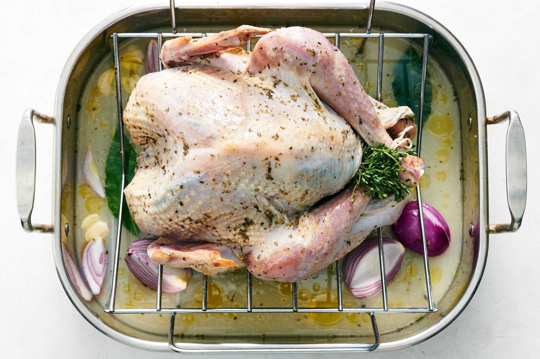 An overhead image of a raw turkey in a roasting pan. 