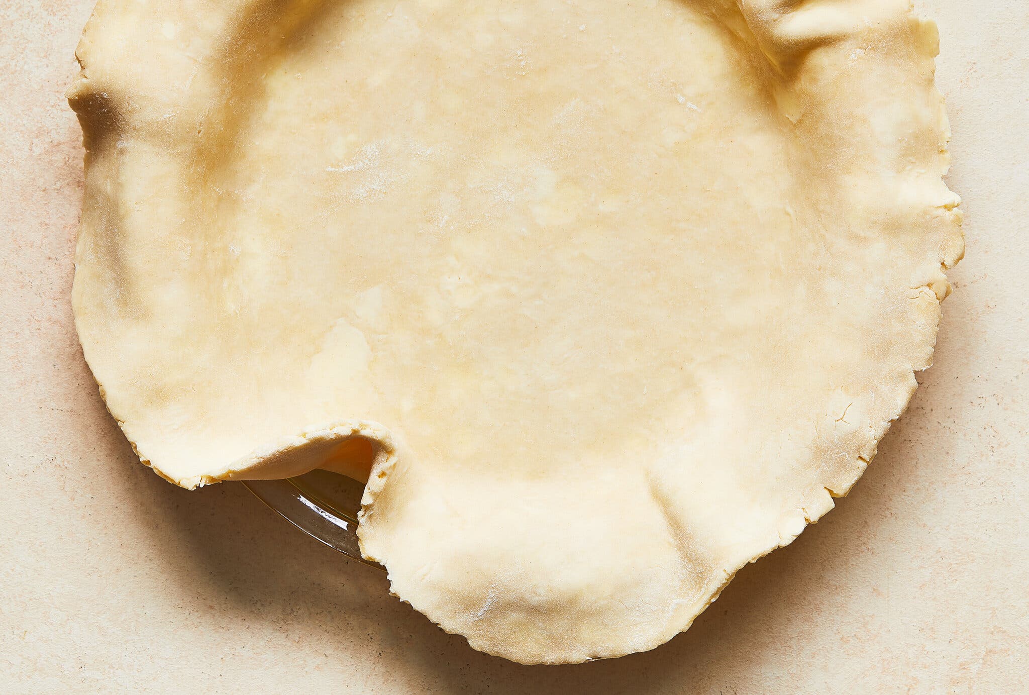 An overhead shot of unbaked pie crust covering a pie dish.