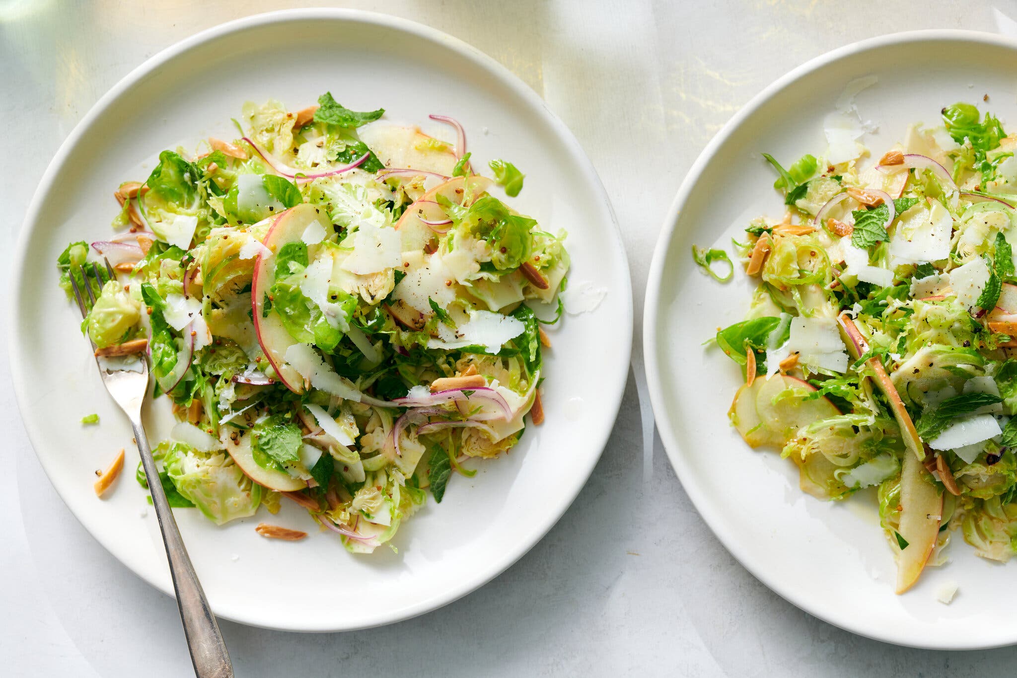 An overhead shot of two plates of brussels sprouts and apple slaw. 