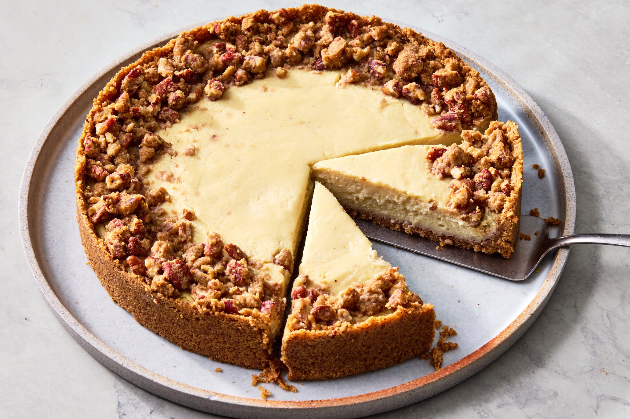 A pie with a creamy filling, a brown crust, and a crumbly topping around the edges. Several slices have been cut.