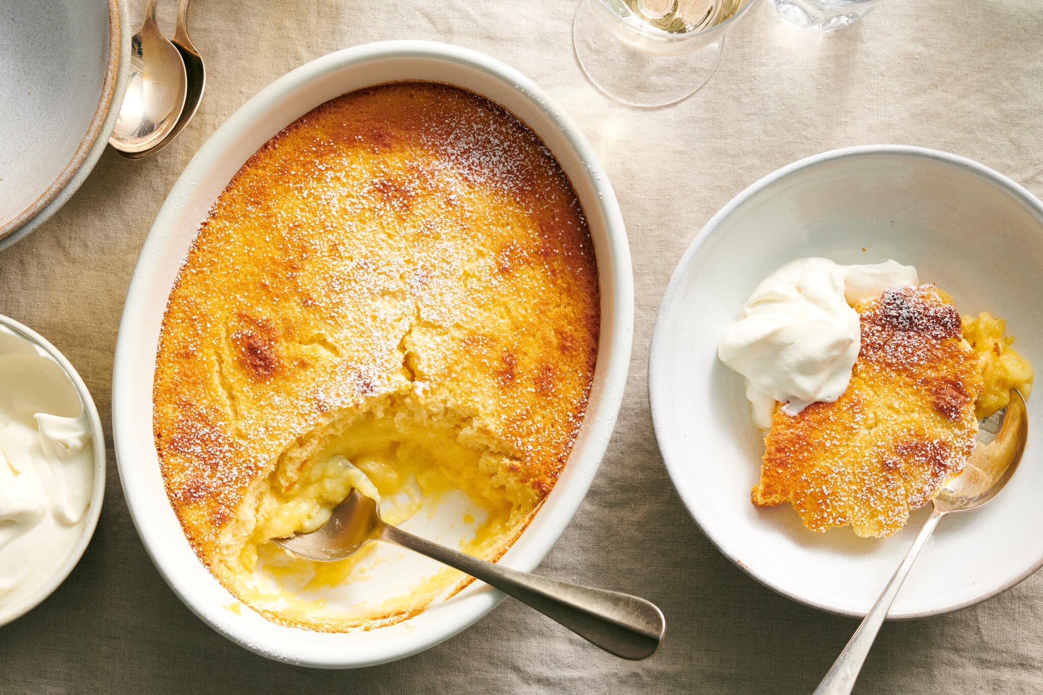 An overhead image of a baking dish filled with lemon pudding. A large serving sits off to the side.