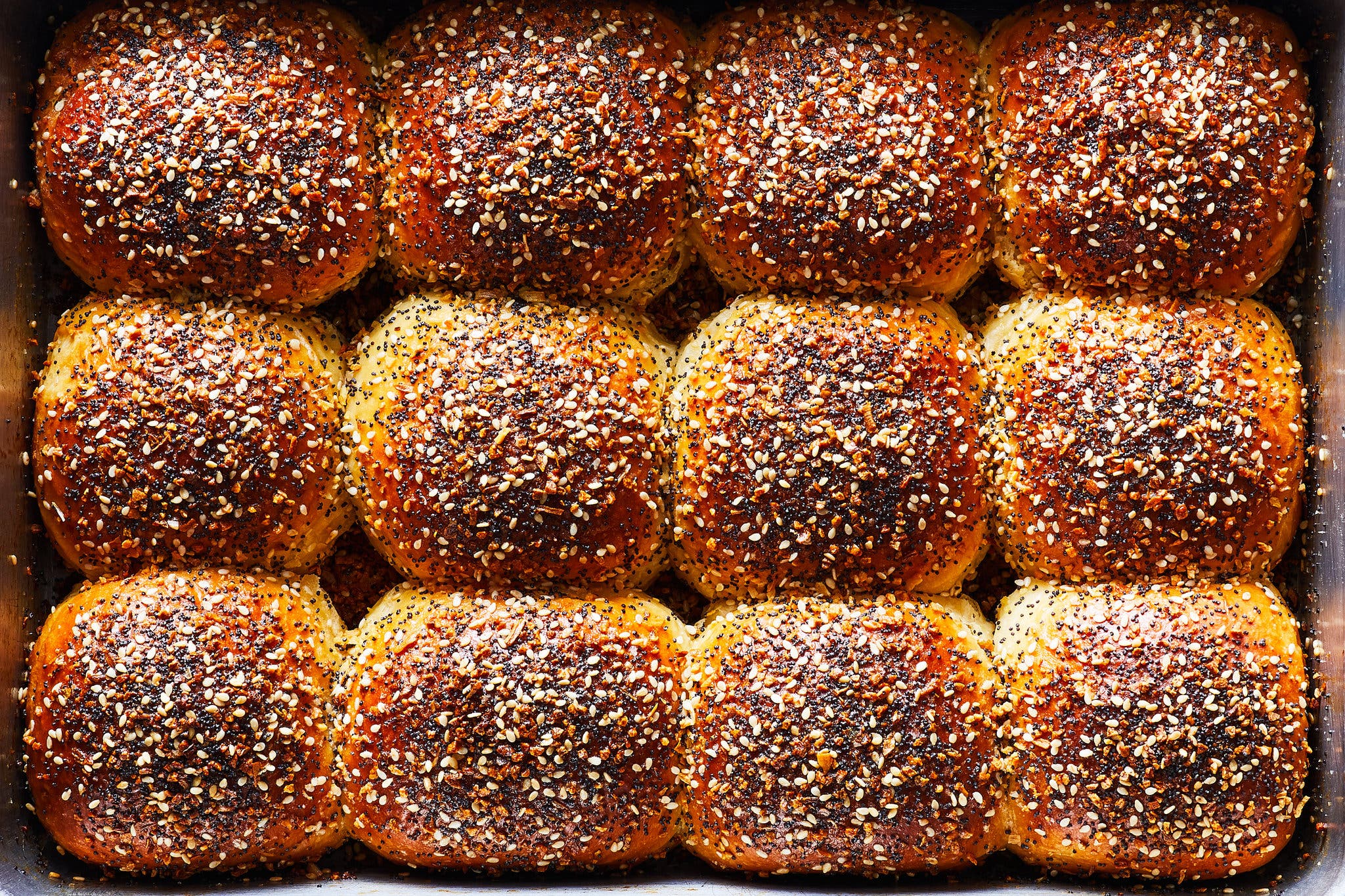 An overhead shot of a dish full of 12 round bread rolls topped with everything seasoning.